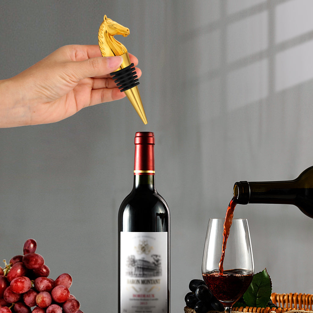 Horse head wine stopper being placed on a wine bottle with a glass of red wine in the background.